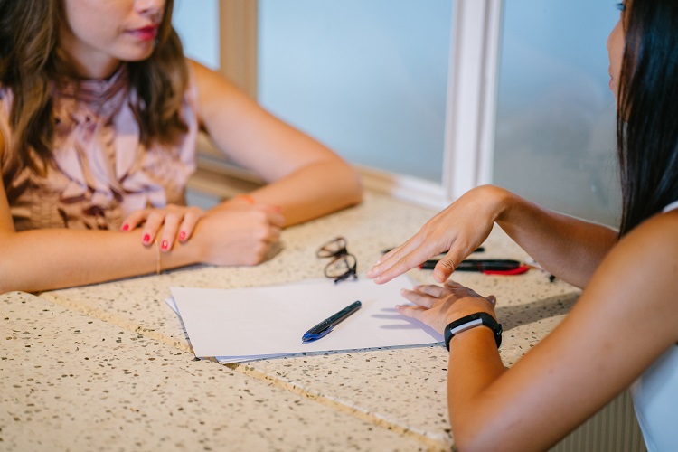 Duas profissionais discutem estratégias de recursos humanos sobre uma mesa com papel e caneta, representando o papel do RH estratégico em médias empresas