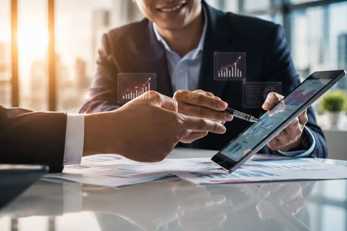 Executivos analisam indicadores em tablet durante reunião de gestão, em contexto de riscos psicossociais e saúde mental no trabalho.